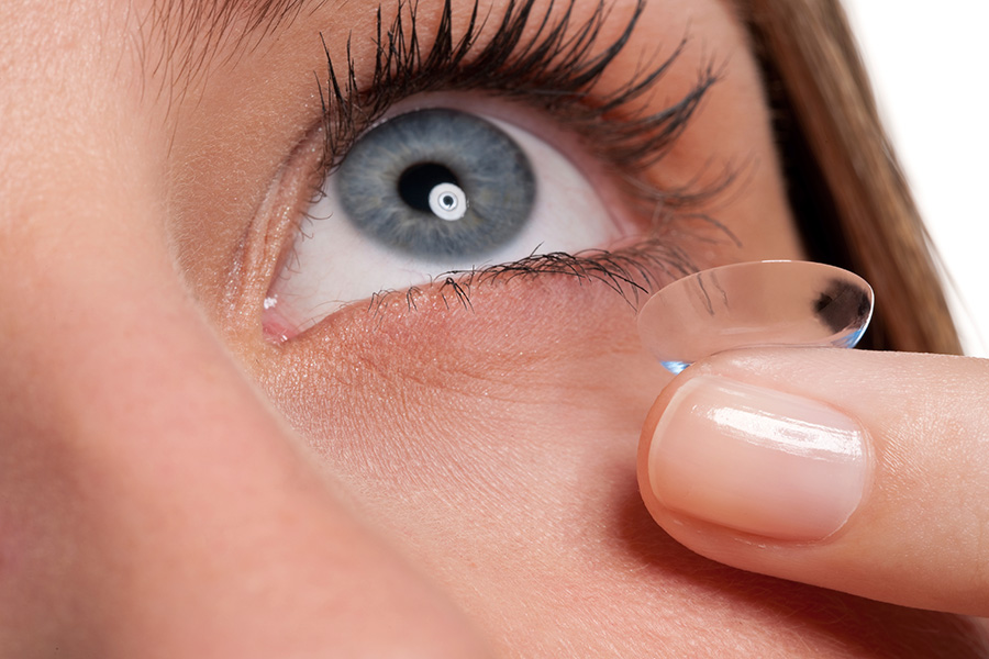 Kobieta zakładająca soczewkę kontaktową na oko